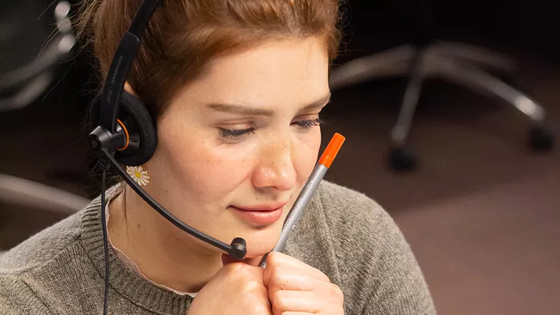 A young woman call center worker taking notes while working