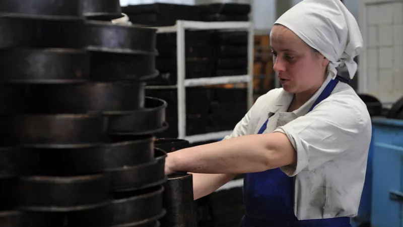 Young woman rearranging cake molds in industrial kitchen