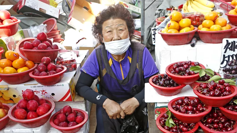 A South Korean merchant sits on street stall with cherry, plum and apricot for sale at Seomun Market.